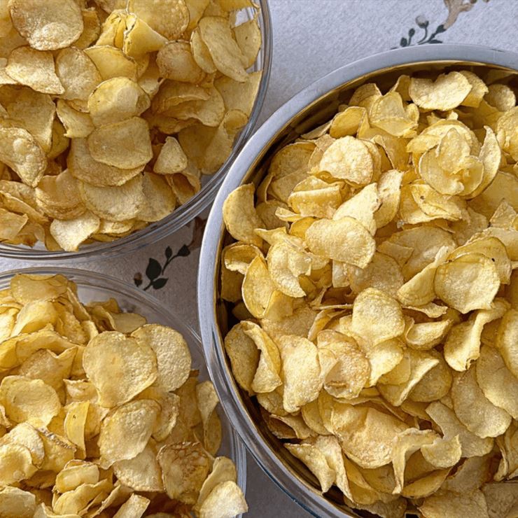 Tri misky remeselných čipsov vyprážaných na hovädzom loji, položené na obruse s moravským vzorom.